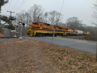 A pair of Providence and Worcester GE Dash-8 locomotives leads a Willimantic-bound freight through the crossing at Packerville